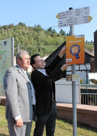 Bild: Ortsbürgermeister Spieß und Verbandsdirektor Heilmann zeigen, wo die Plakette befestigt wird.