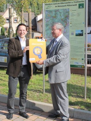 Bild: Verbandsdirektor Heilmann überreicht die Plakette an Ortsbürgermeister Spieß.
